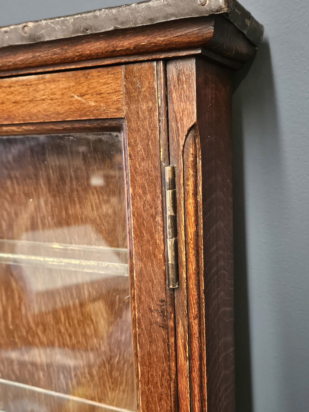 An Edwardian warm brown oak wall-mounted display cabinet with a single glass door featuring gold lettering that reads OPTICIAN over internal glass shelves. View IV