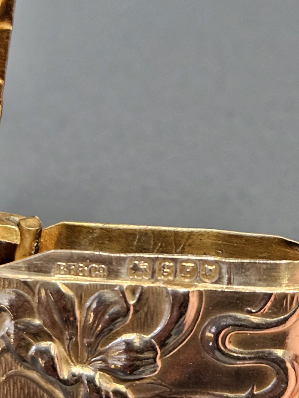 An Art Nouveau sterling silver vesta case featuring embossed floral motifs and whiplash scroll decoration with visible British hallmarks and a side suspension ring. View VII
