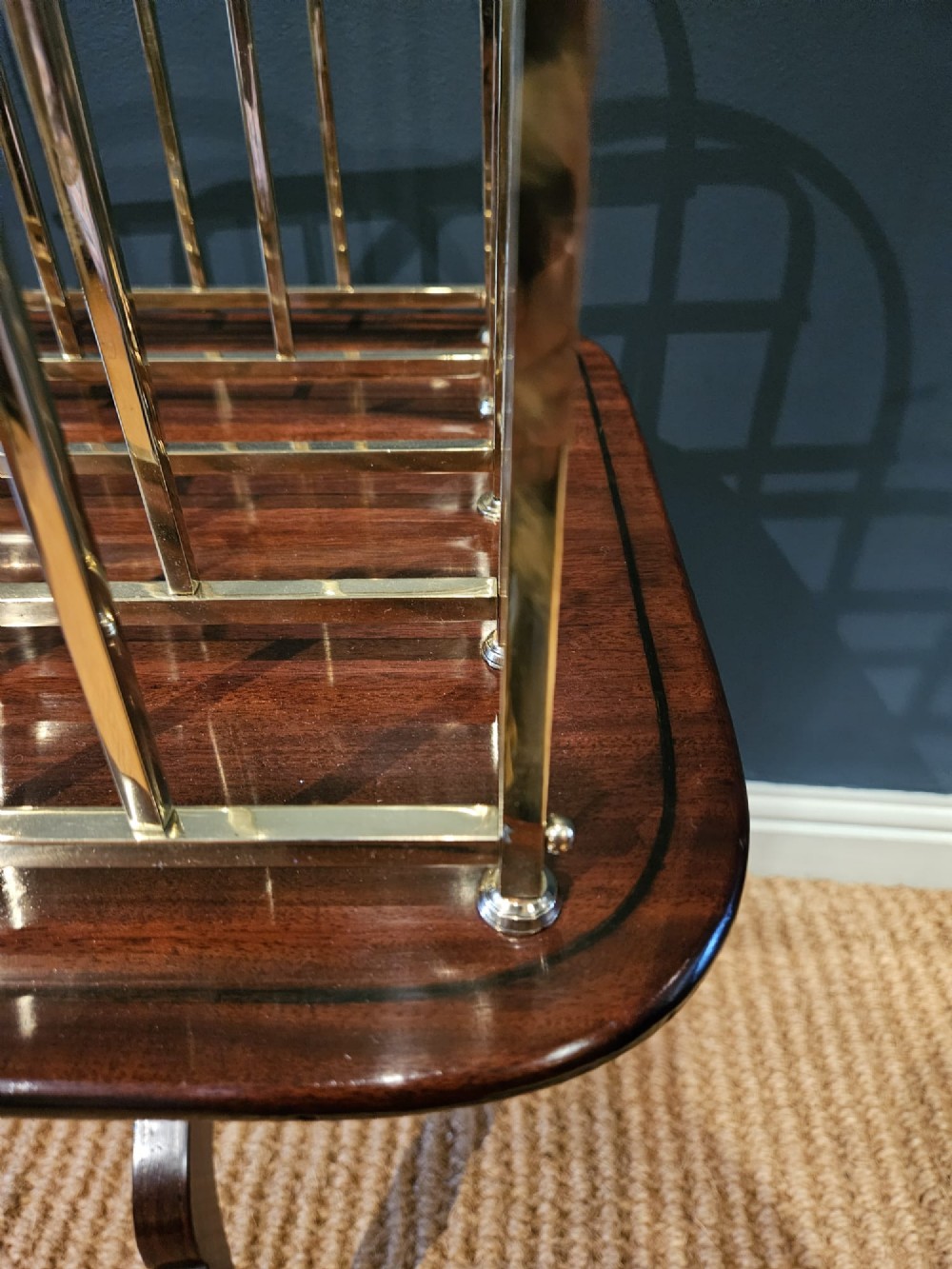 A Victorian brass magazine rack with vertical partitioned dividers mounted atop a polished mahogany tripod table base. View III
