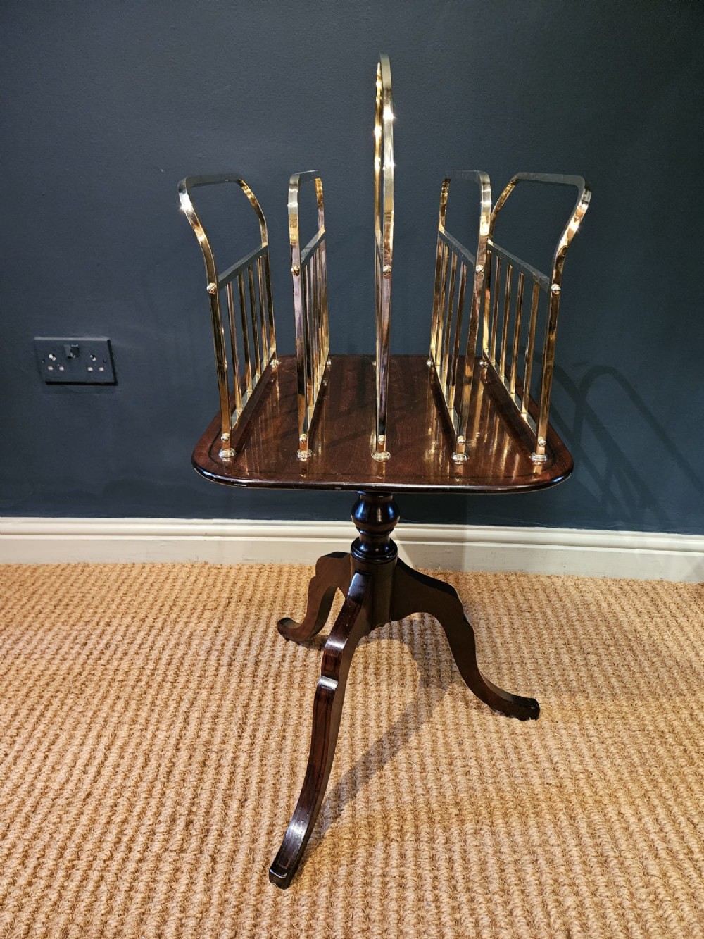 A Victorian brass magazine rack with vertical partitioned dividers mounted atop a polished mahogany tripod table base. View V
