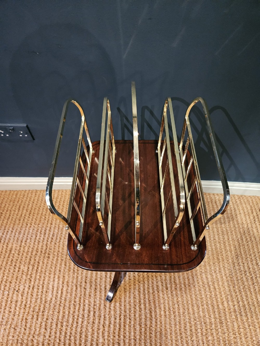 A Victorian brass magazine rack with vertical partitioned dividers mounted atop a polished mahogany tripod table base. View VII
