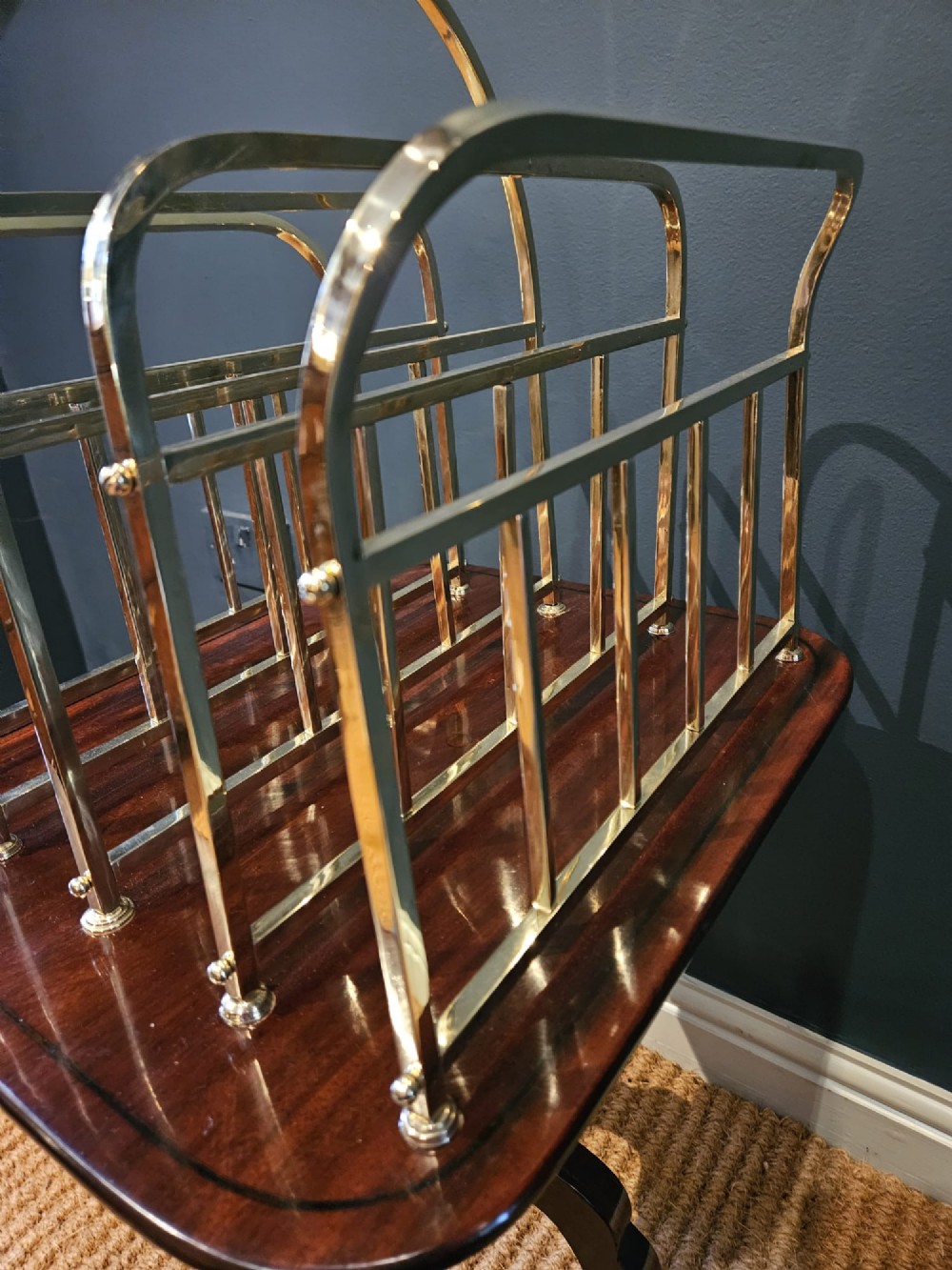 A Victorian brass magazine rack with vertical partitioned dividers mounted atop a polished mahogany tripod table base. View VIII