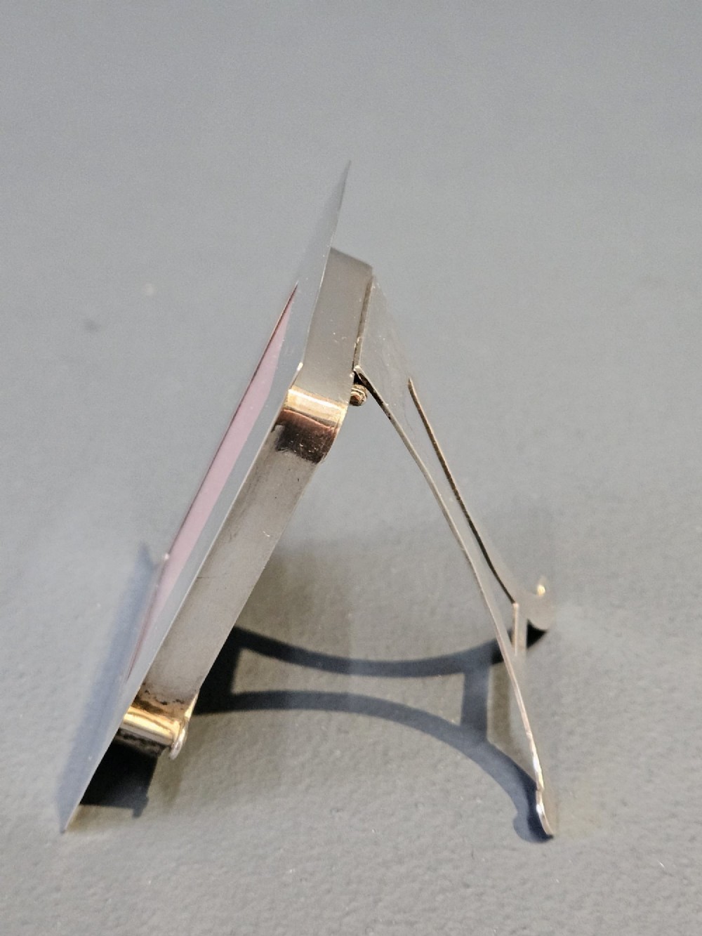 A small rectangular Edwardian polished silver photo frame featuring a plain border and a pink textured insert. View II