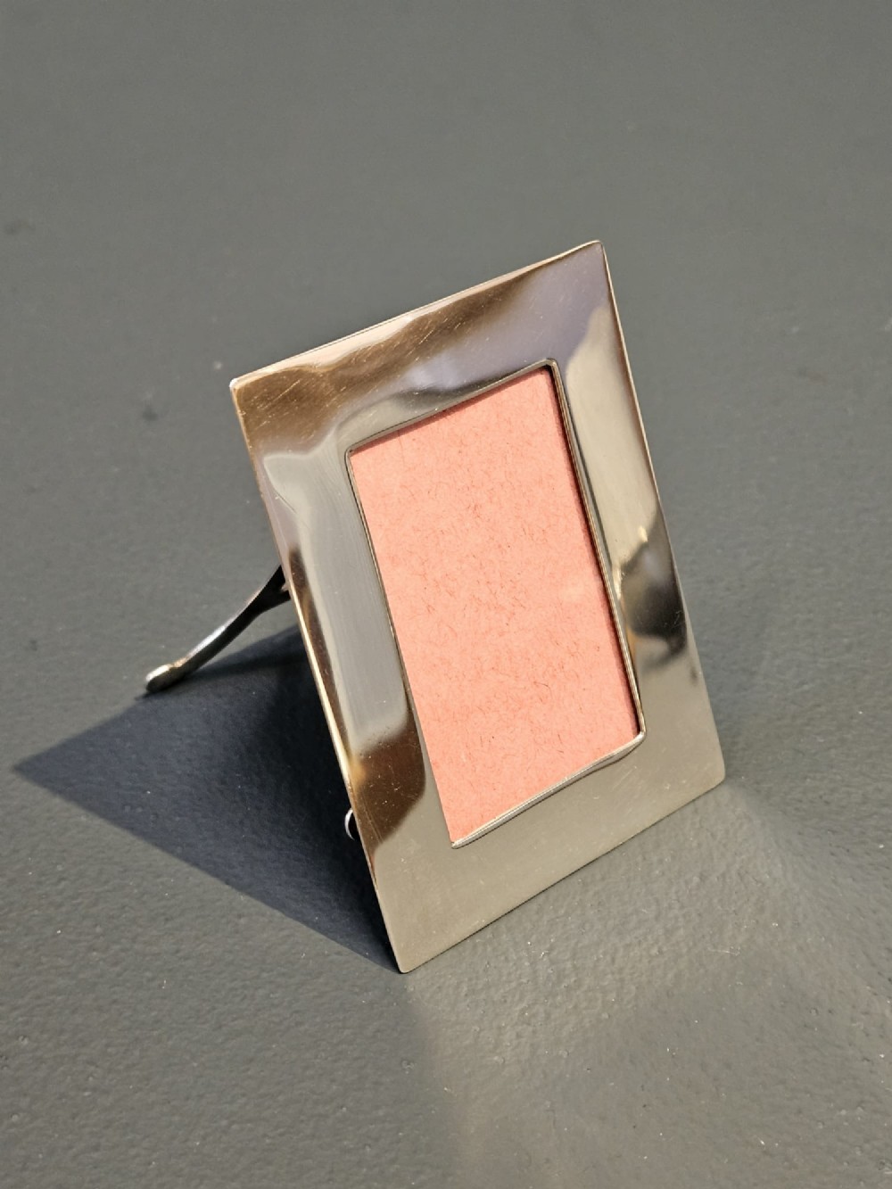 A small rectangular Edwardian polished silver photo frame featuring a plain border and a pink textured insert. View III