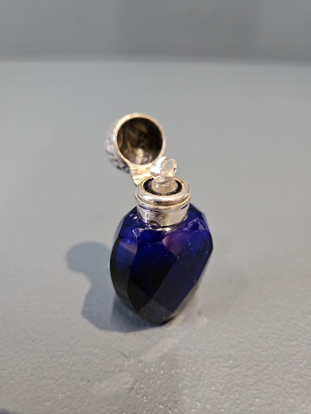 A Victorian faceted cobalt blue glass scent bottle with an engraved sterling silver cap. View V