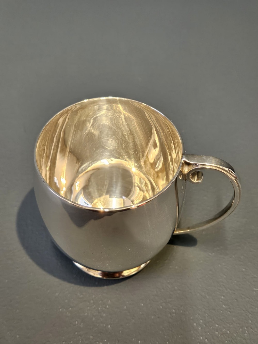 A polished silver mug featuring a bulbous body, a stepped base, and a scroll handle. View II