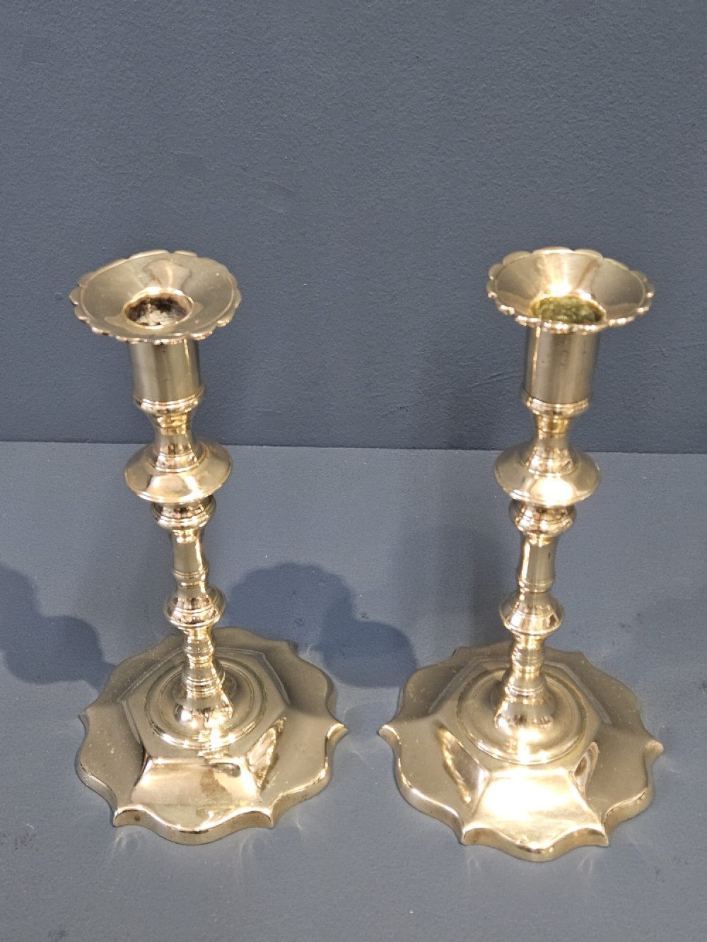 A pair of cast George II brass candlesticks featuring knopped baluster stems and lobed petal-shaped bases. View II