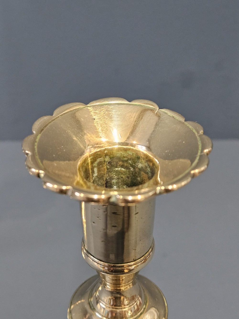 A pair of cast George II brass candlesticks featuring knopped baluster stems and lobed petal-shaped bases. View IV