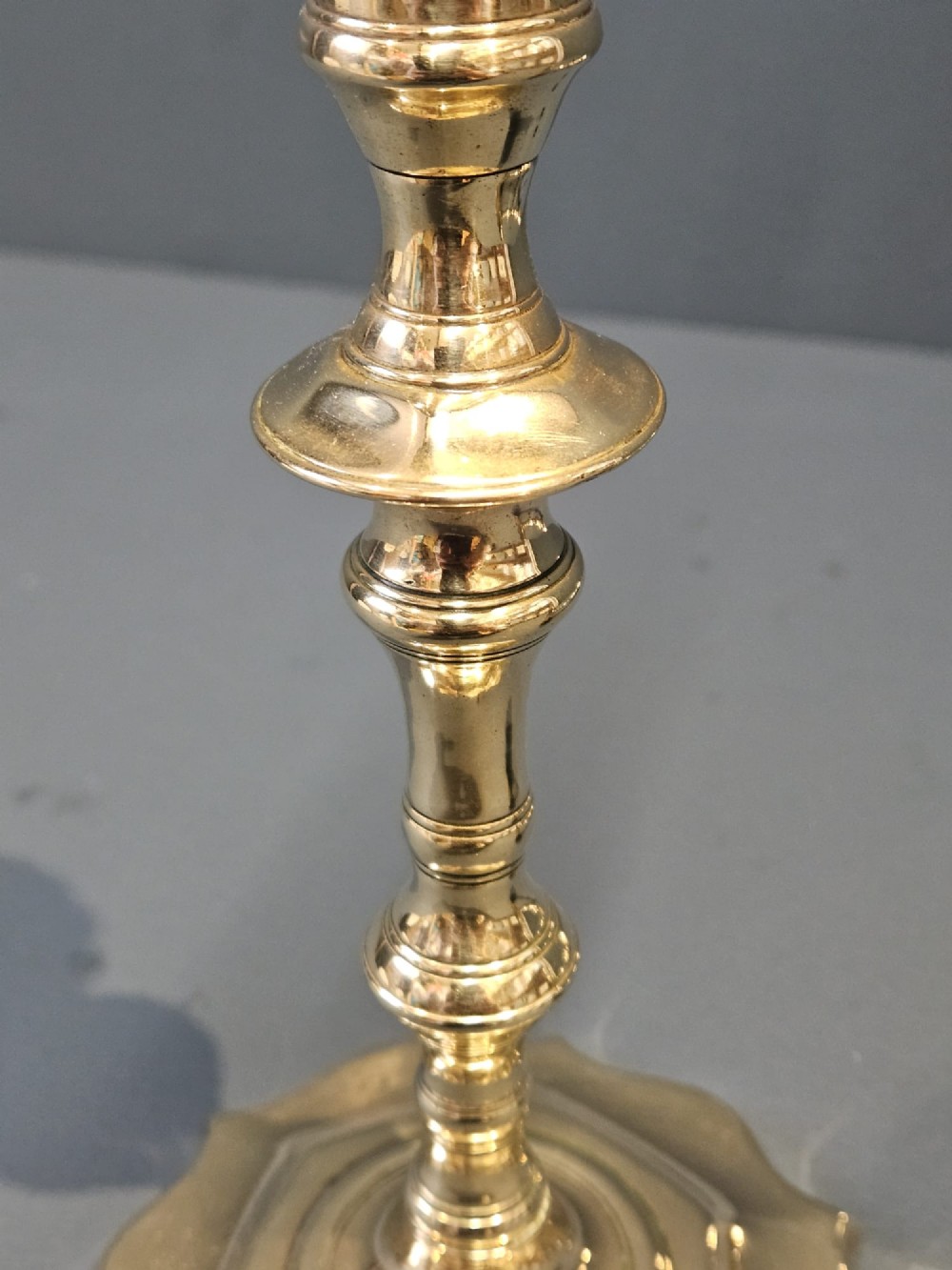 A pair of cast George II brass candlesticks featuring knopped baluster stems and lobed petal-shaped bases. View V
