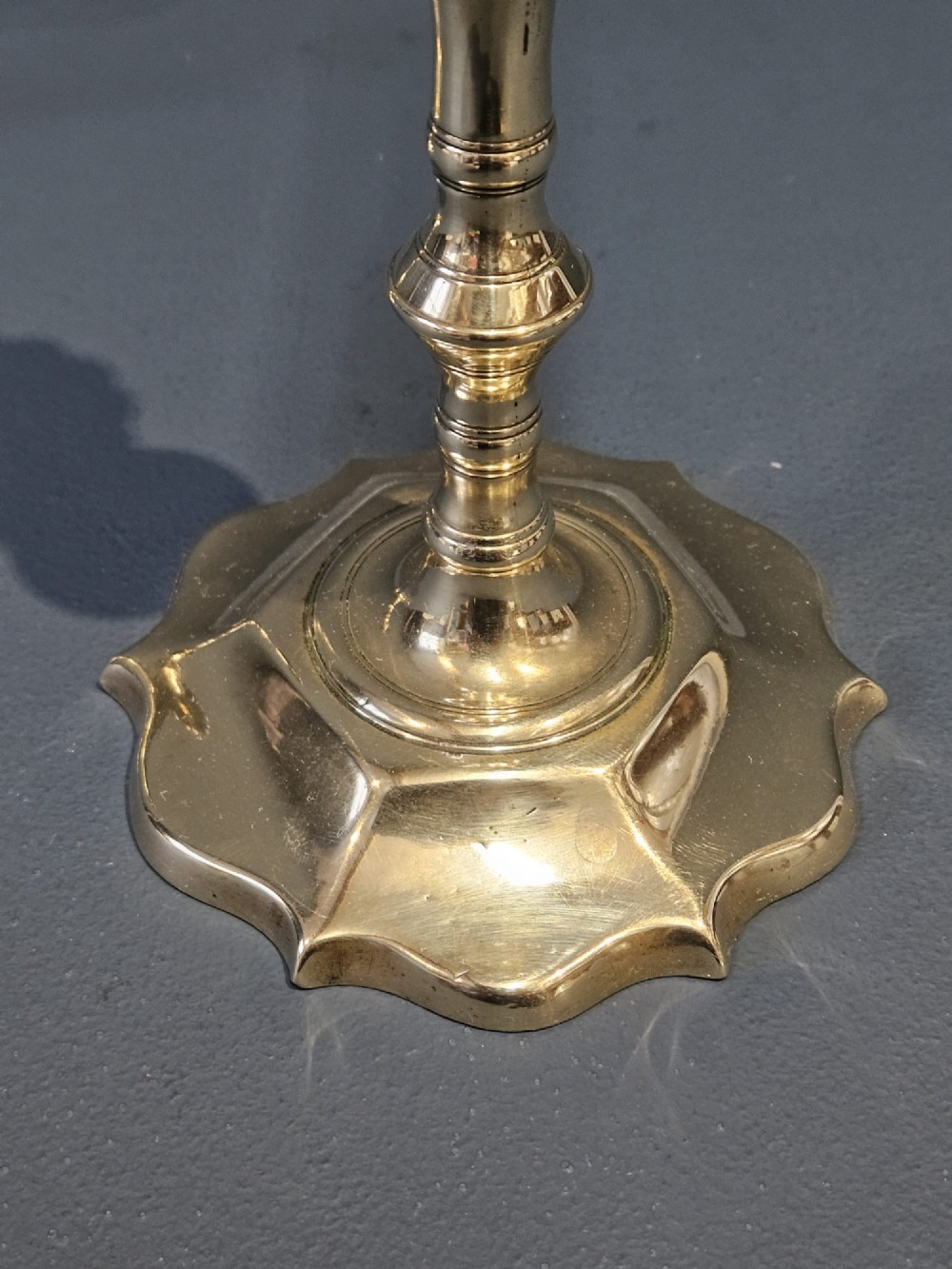 A pair of cast George II brass candlesticks featuring knopped baluster stems and lobed petal-shaped bases. View VI
