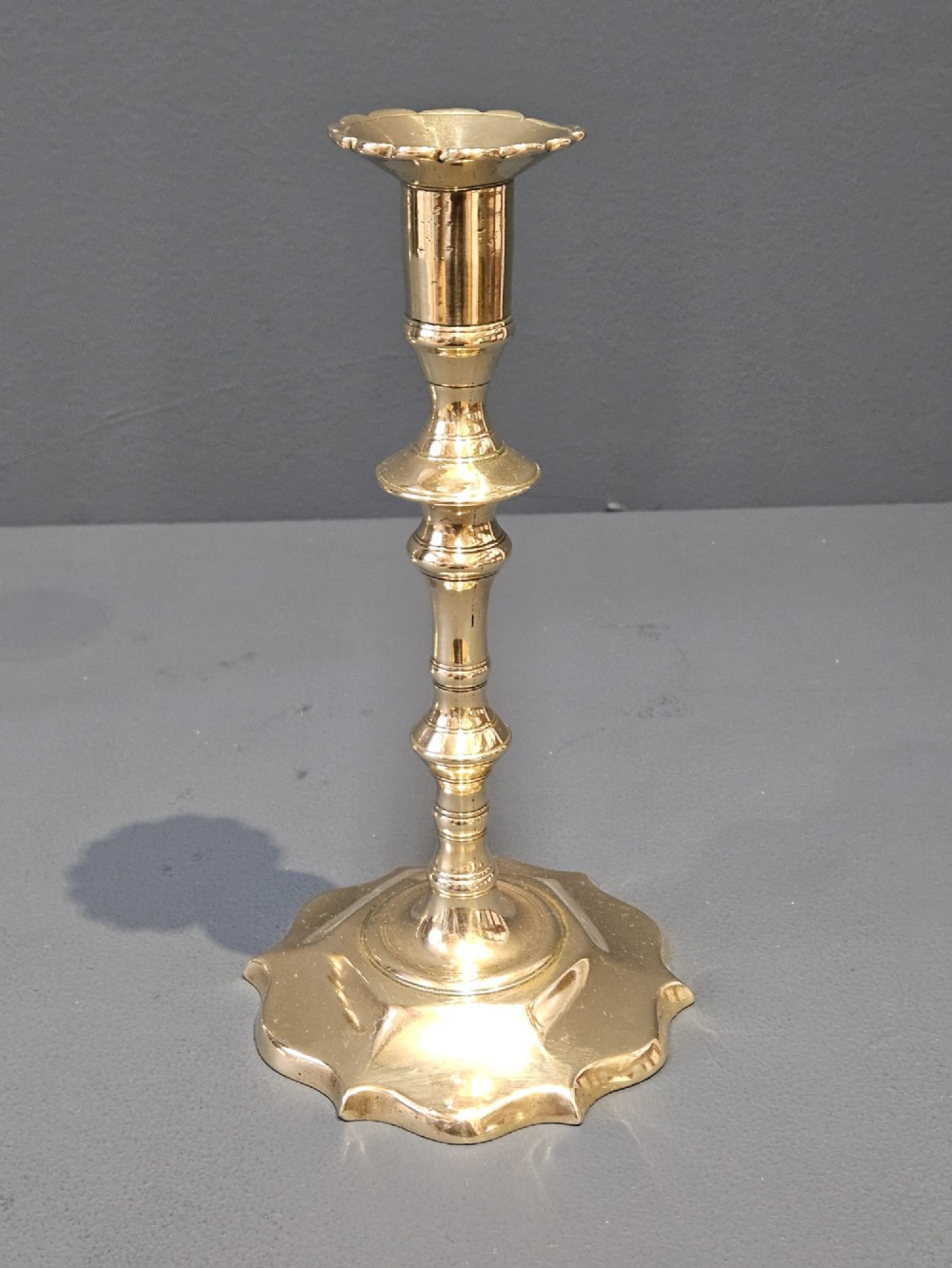 A pair of cast George II brass candlesticks featuring knopped baluster stems and lobed petal-shaped bases. View VII