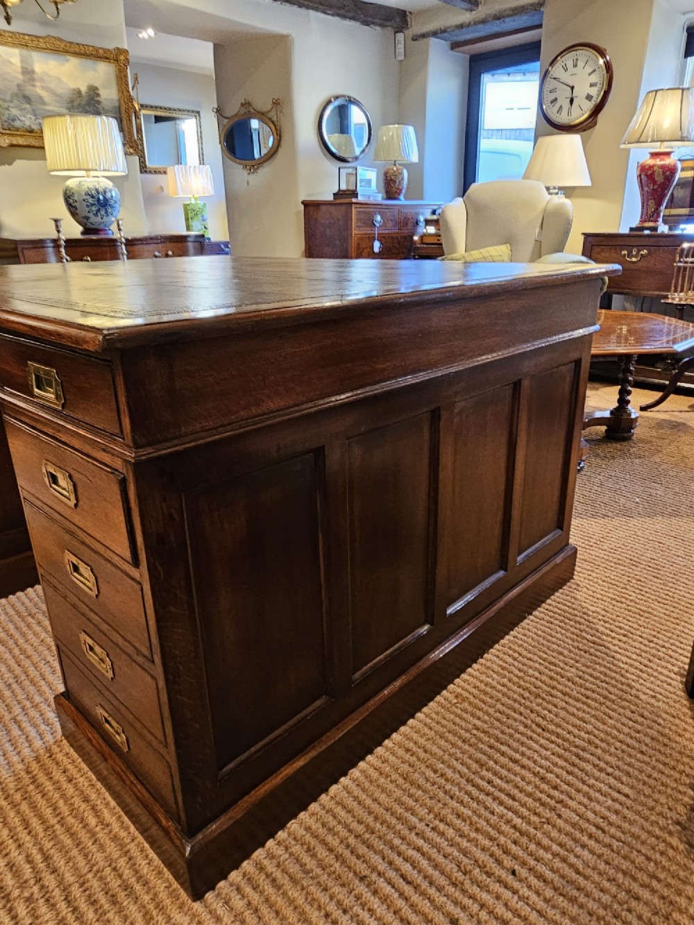 A large Victorian dark oak partners desk featuring dual twin pedestals, inset brass campaign handles, and a leather-topped writing surface. View X