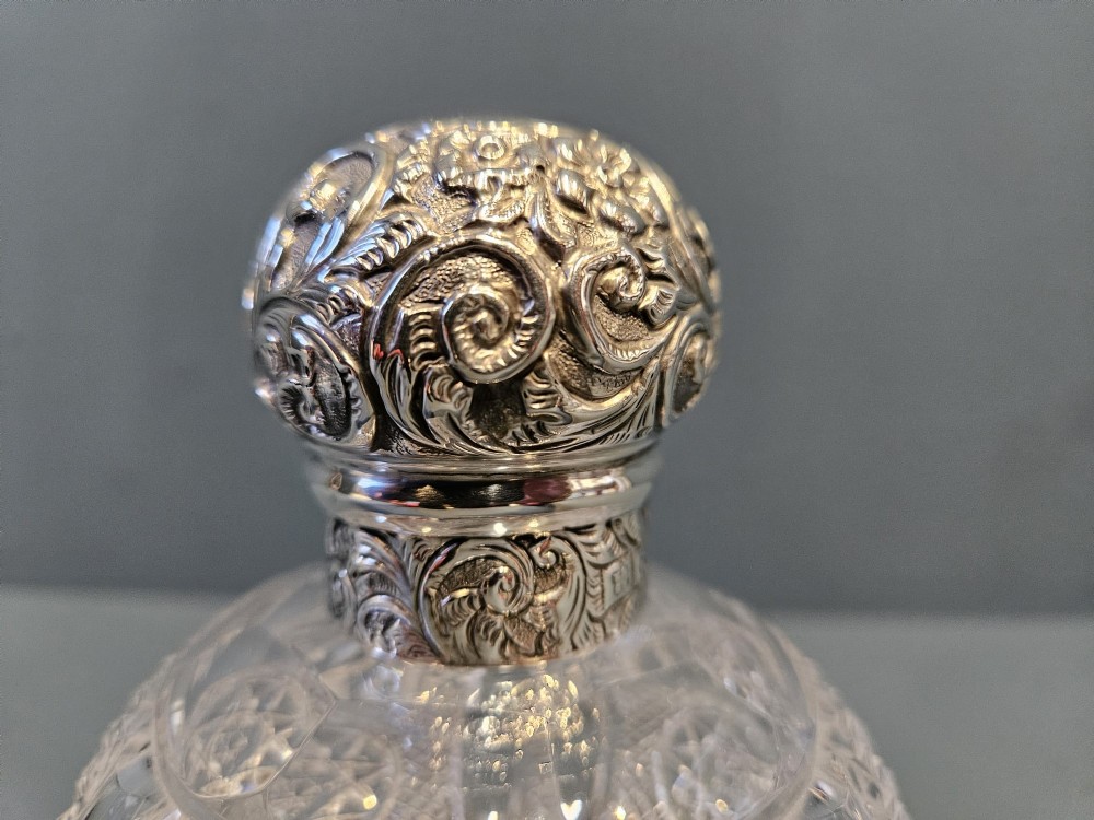 A late Victorian clear cut crystal scent bottle featuring a spherical body with a starburst pattern and an embossed silver cap. View II