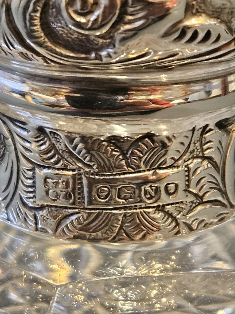 A late Victorian clear cut crystal scent bottle featuring a spherical body with a starburst pattern and an embossed silver cap. View IV