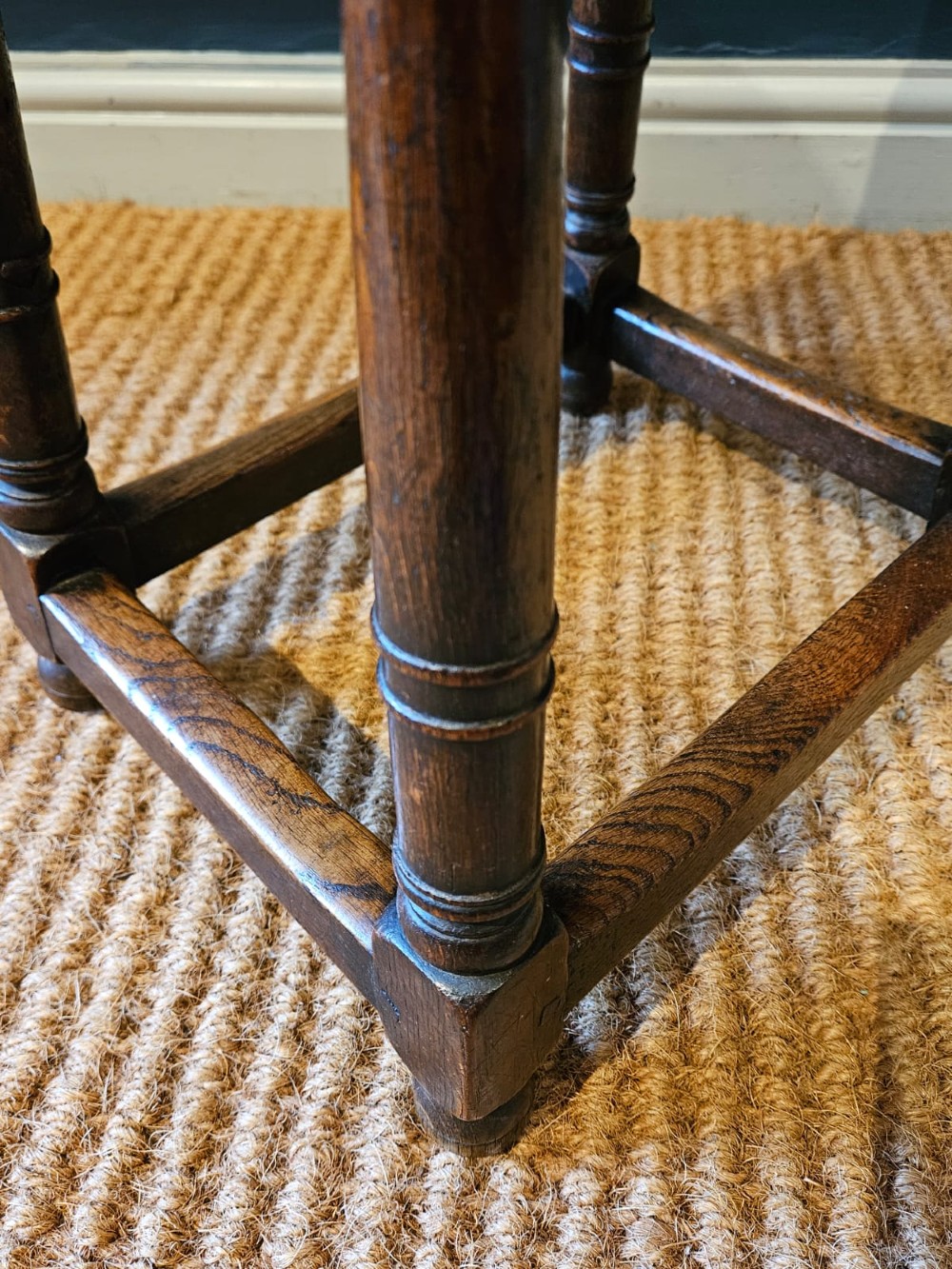 An antique dark oak joint stool featuring a rectangular top, moulded frieze, turned legs, and lower perimeter stretchers. View V