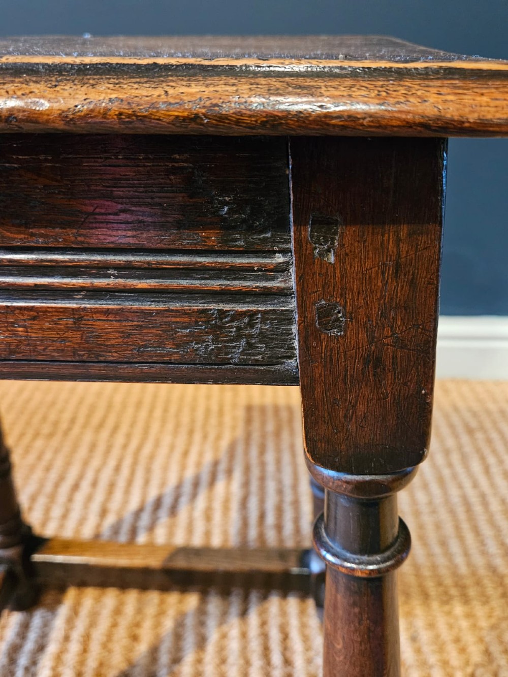 An antique dark oak joint stool featuring a rectangular top, moulded frieze, turned legs, and lower perimeter stretchers. View VI