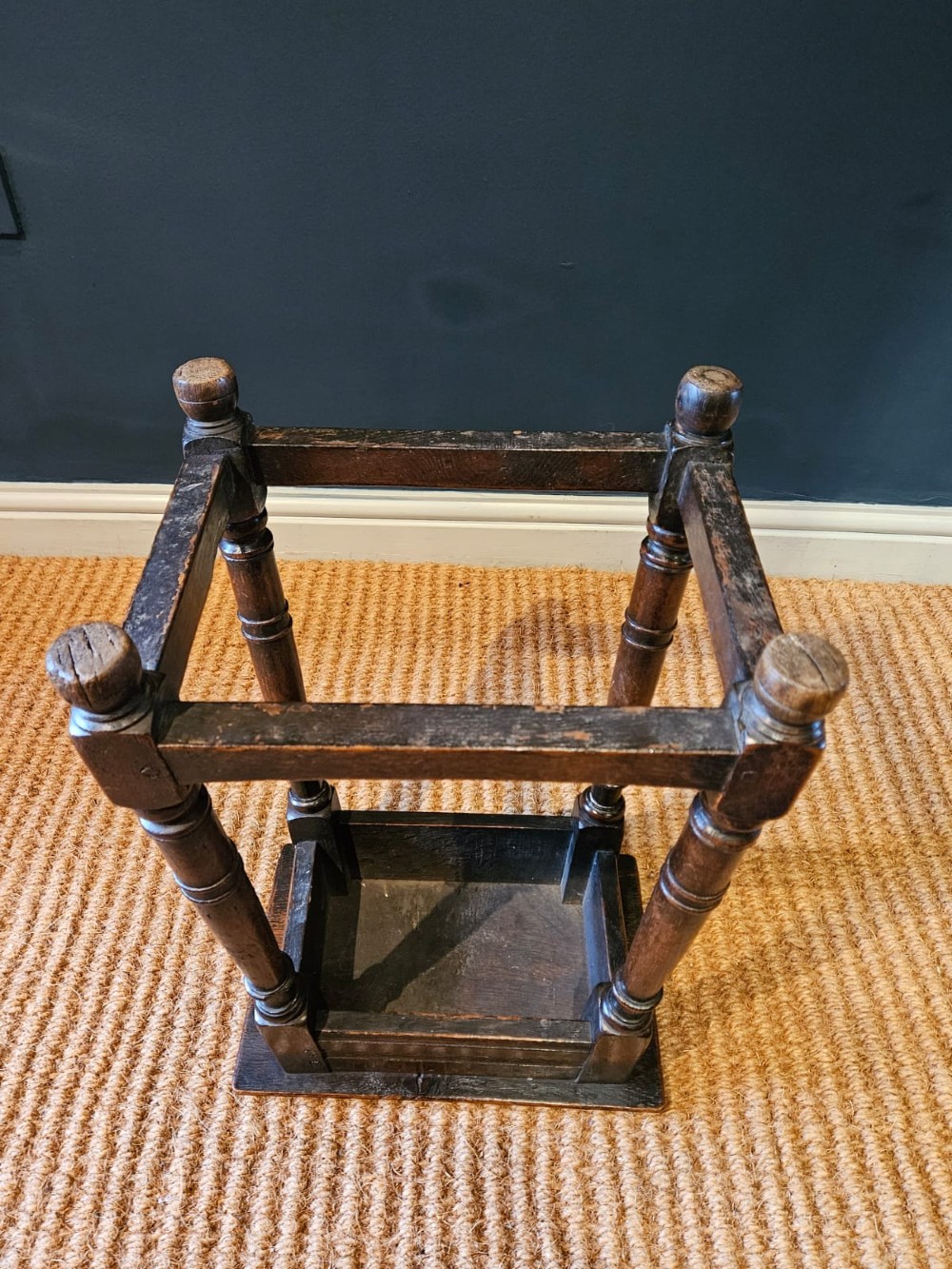 An antique dark oak joint stool featuring a rectangular top, moulded frieze, turned legs, and lower perimeter stretchers. View VII
