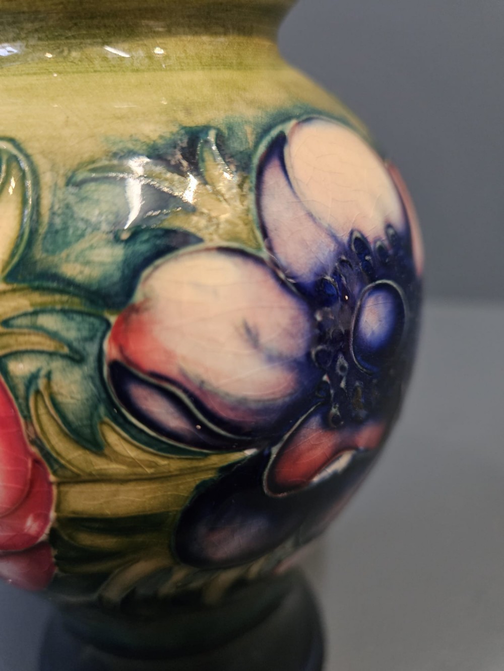 A small baluster-shaped ceramic vase featuring a tubelined red anemone motif against a ground fading from yellow-green to dark blue. View V