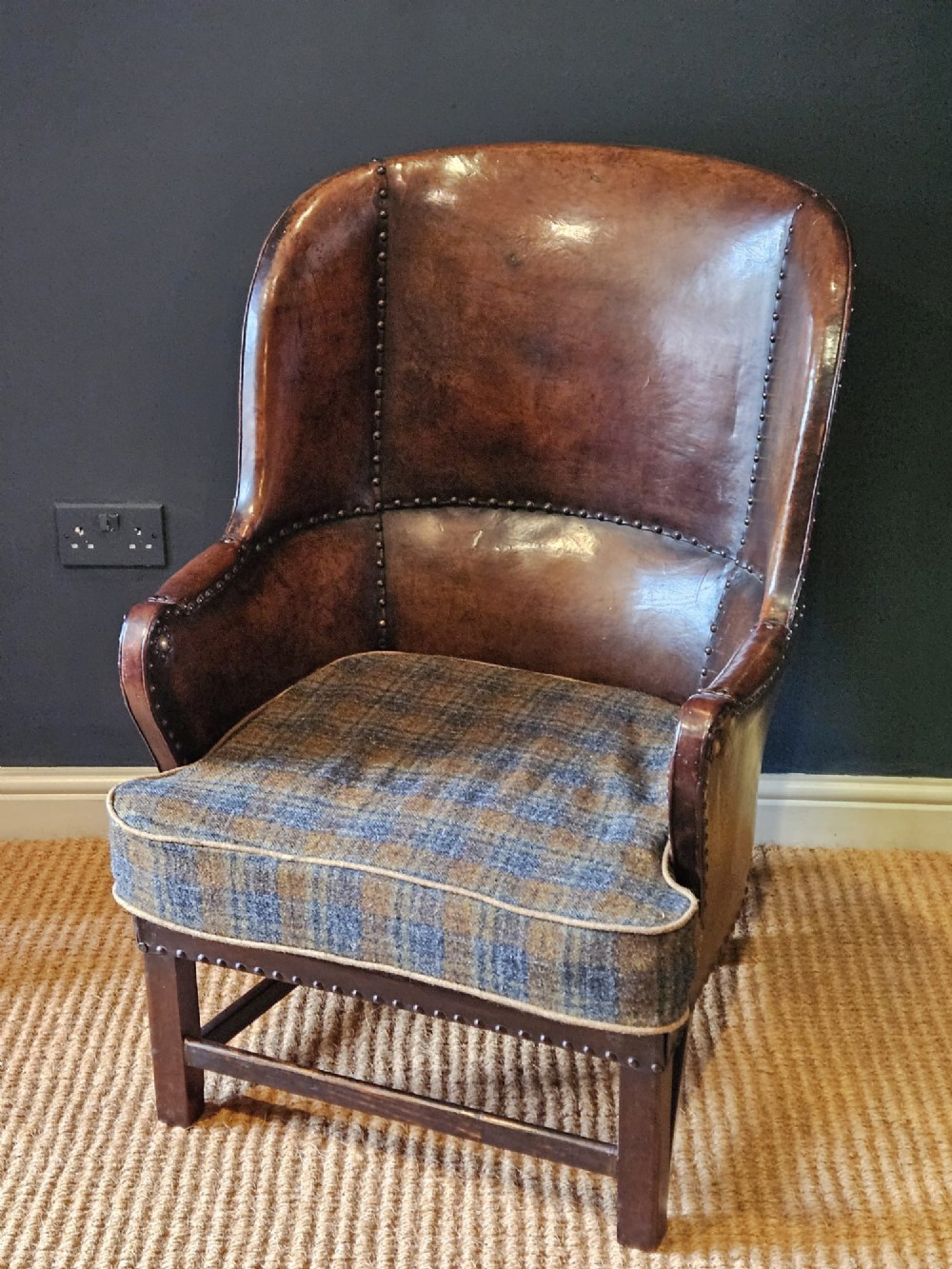 An Arts and Crafts brown leather fireside armchair featuring brass studding, an oak frame, and a woven plaid fabric seat cushion. View IV