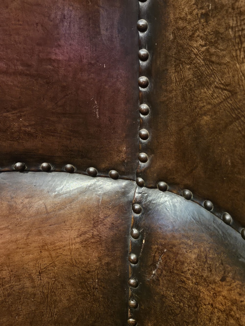 An Arts and Crafts brown leather fireside armchair featuring brass studding, an oak frame, and a woven plaid fabric seat cushion. View VI