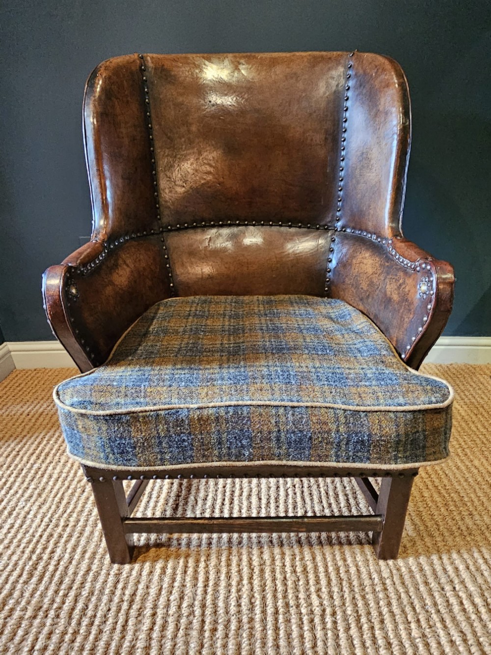 An Arts and Crafts brown leather fireside armchair featuring brass studding, an oak frame, and a woven plaid fabric seat cushion. View XI