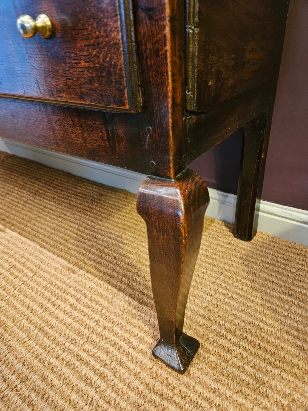 A low George II dark oak dresser base featuring three inline drawers with brass knob handles, set on front cabriole legs. View III