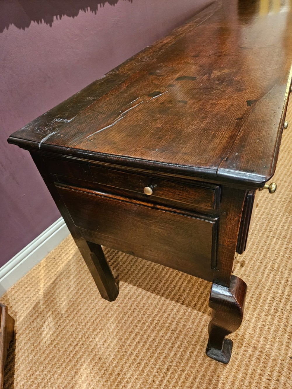 A low George II dark oak dresser base featuring three inline drawers with brass knob handles, set on front cabriole legs. View IX