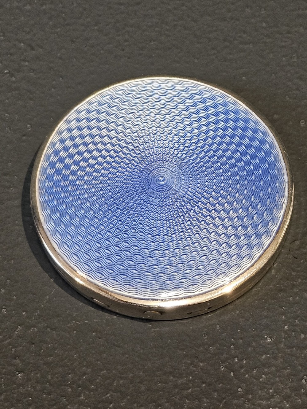 A circular silver compact featuring a vibrant blue engine-turned guilloche enamel lid with a radiating pattern. View II