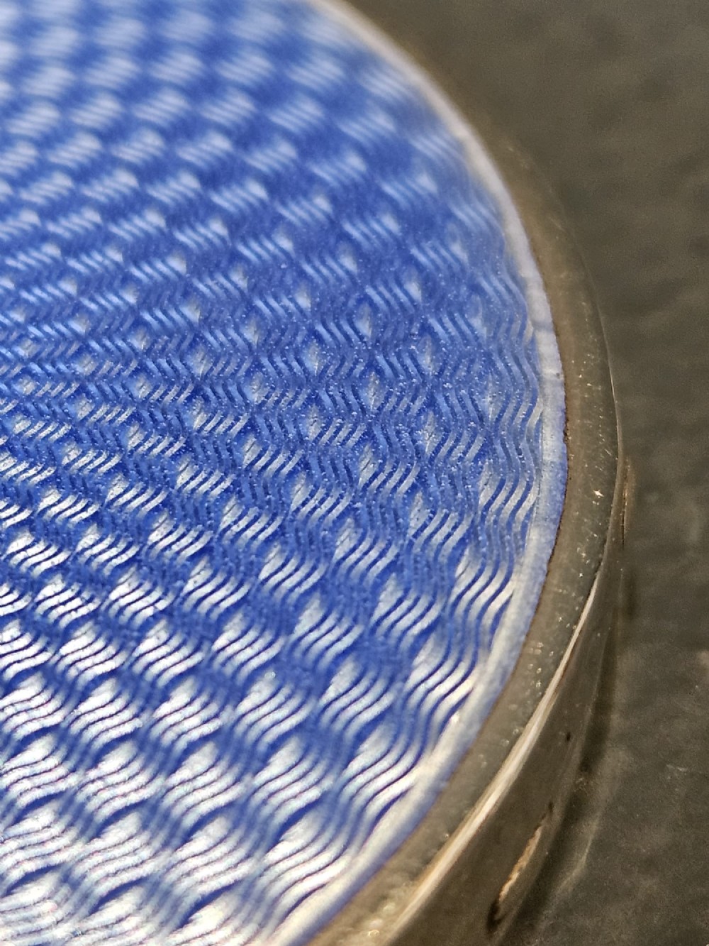 A circular silver compact featuring a vibrant blue engine-turned guilloche enamel lid with a radiating pattern. View IV