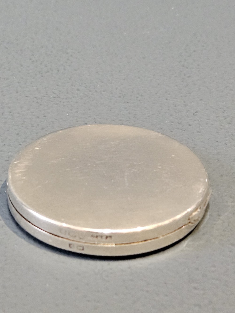 A circular silver compact featuring a vibrant blue engine-turned guilloche enamel lid with a radiating pattern. View V