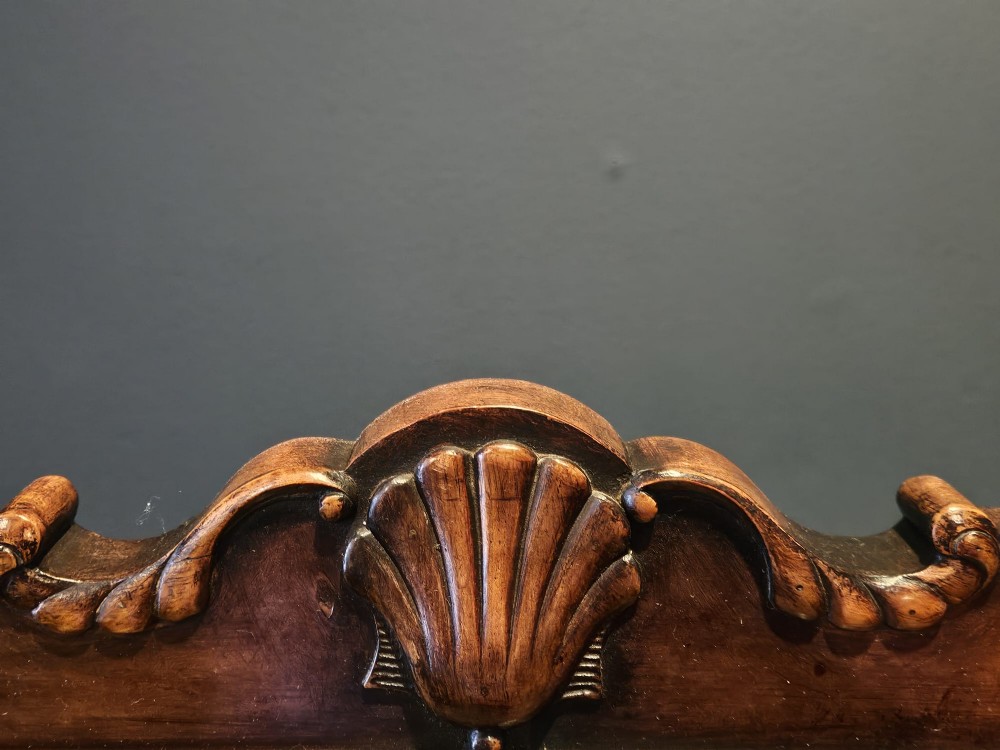 A George III style mahogany cheval mirror featuring an arched top with a carved shell cresting, turned side finials, and splayed legs on brass castors. View III