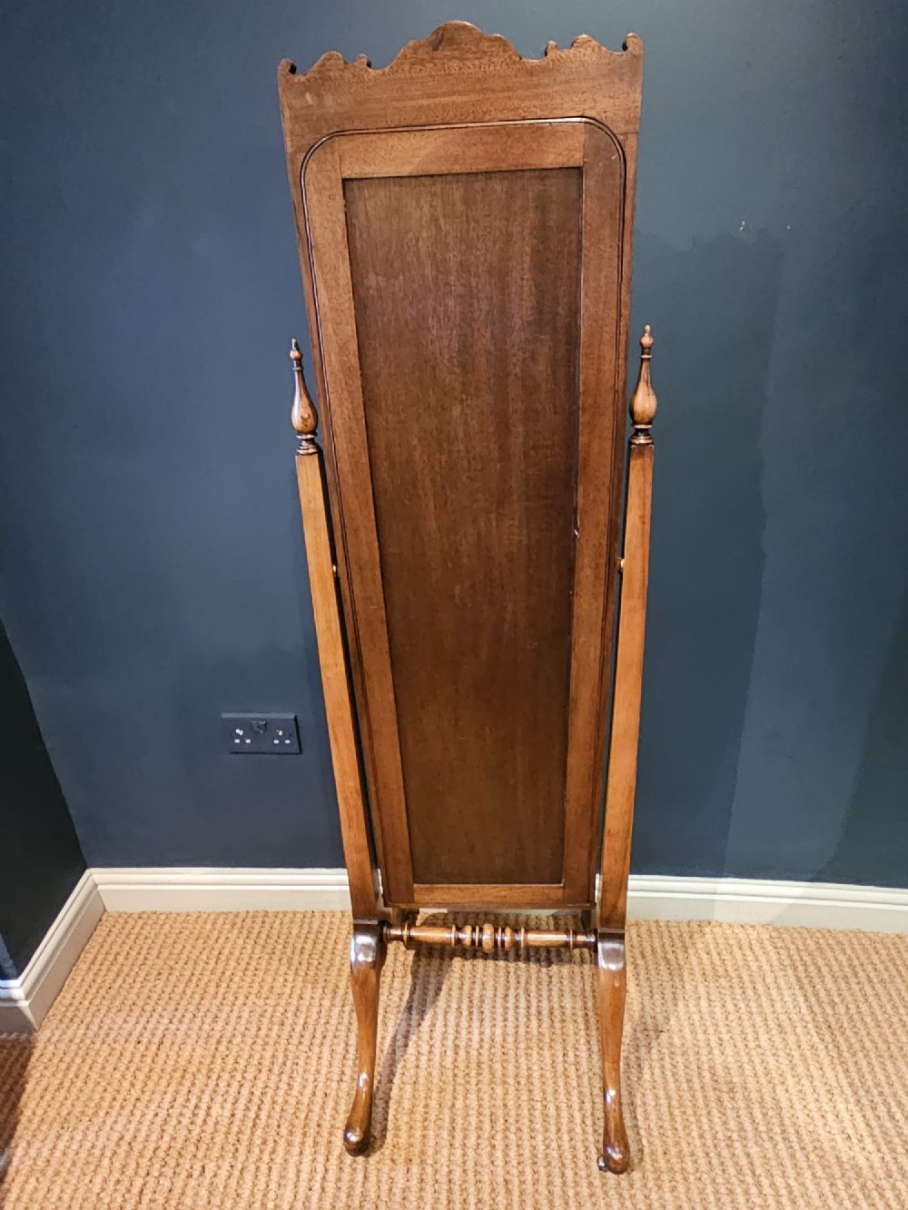 A George III style mahogany cheval mirror featuring an arched top with a carved shell cresting, turned side finials, and splayed legs on brass castors. View V