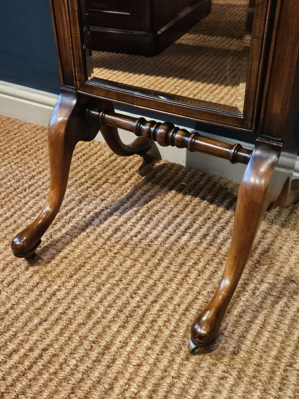 A George III style mahogany cheval mirror featuring an arched top with a carved shell cresting, turned side finials, and splayed legs on brass castors. View VII