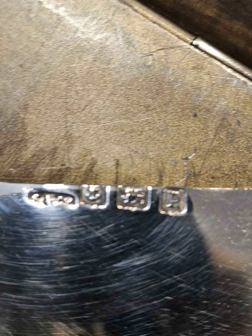 An antique sterling silver envelope-shaped card case with visible hallmarks along the flap seam resting against a dark grey backdrop. View III