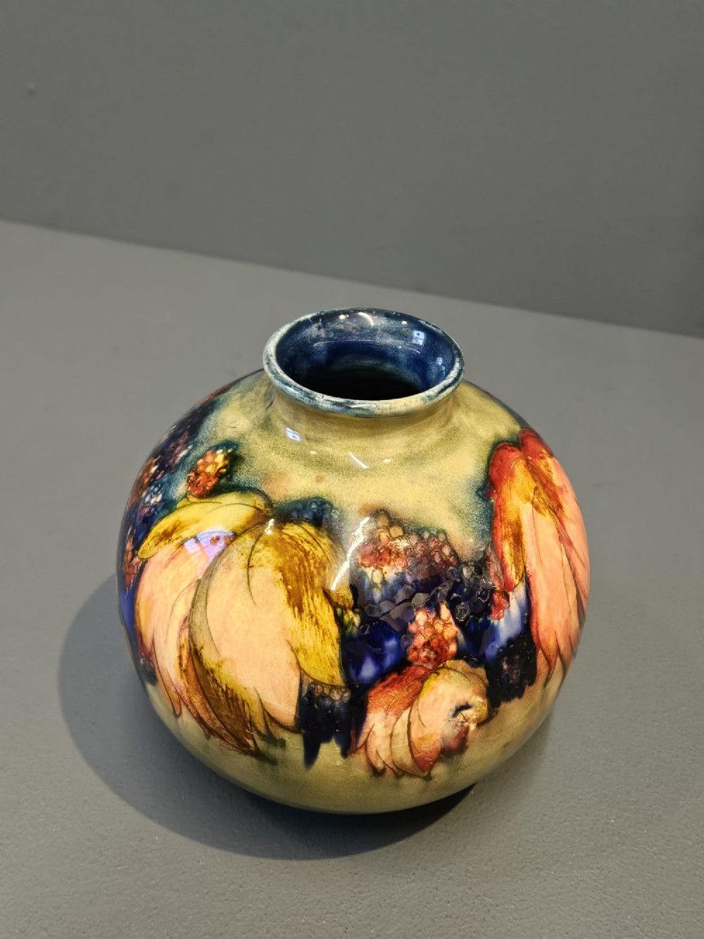 A spherical Moorcroft pottery vase decorated with a tubelined leaf and blackberry pattern under a glossy flambe glaze. View VI