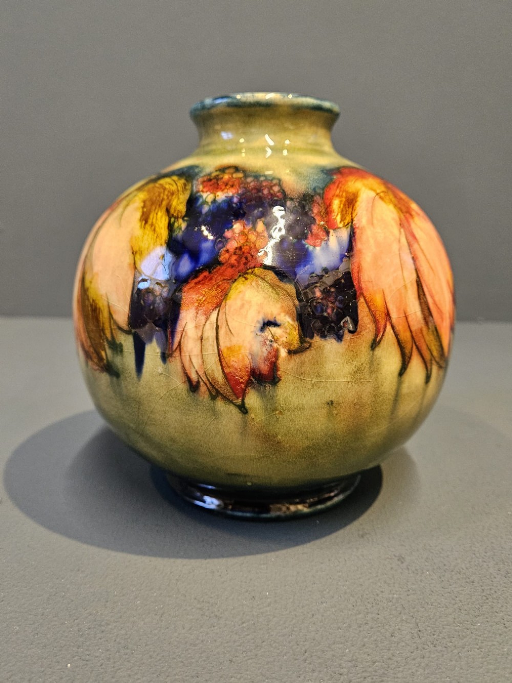 A spherical Moorcroft pottery vase decorated with a tubelined leaf and blackberry pattern under a glossy flambe glaze. View VII