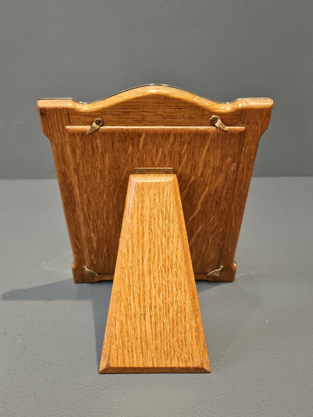 A sterling silver photo frame featuring a swept arched top, moulded border, visible hallmarks at the base, and a green fabric backing. View III
