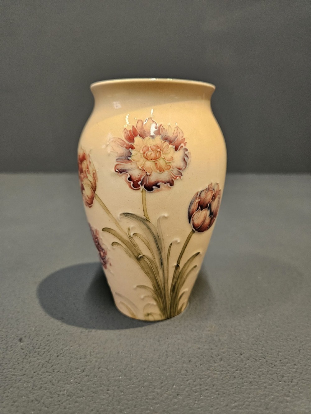 A cream earthenware vase decorated with tubelined pink cornflowers and green foliage in an Art Nouveau design. View II