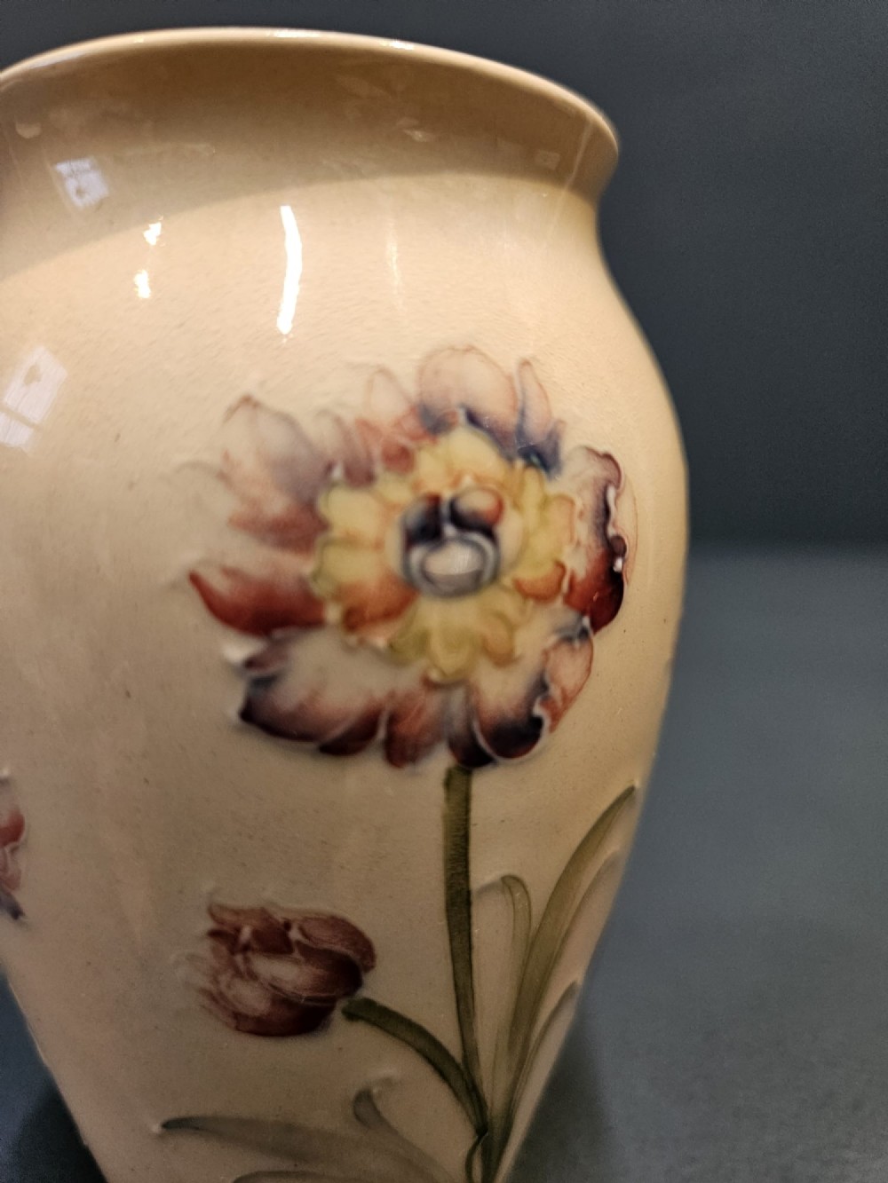 A cream earthenware vase decorated with tubelined pink cornflowers and green foliage in an Art Nouveau design. View III
