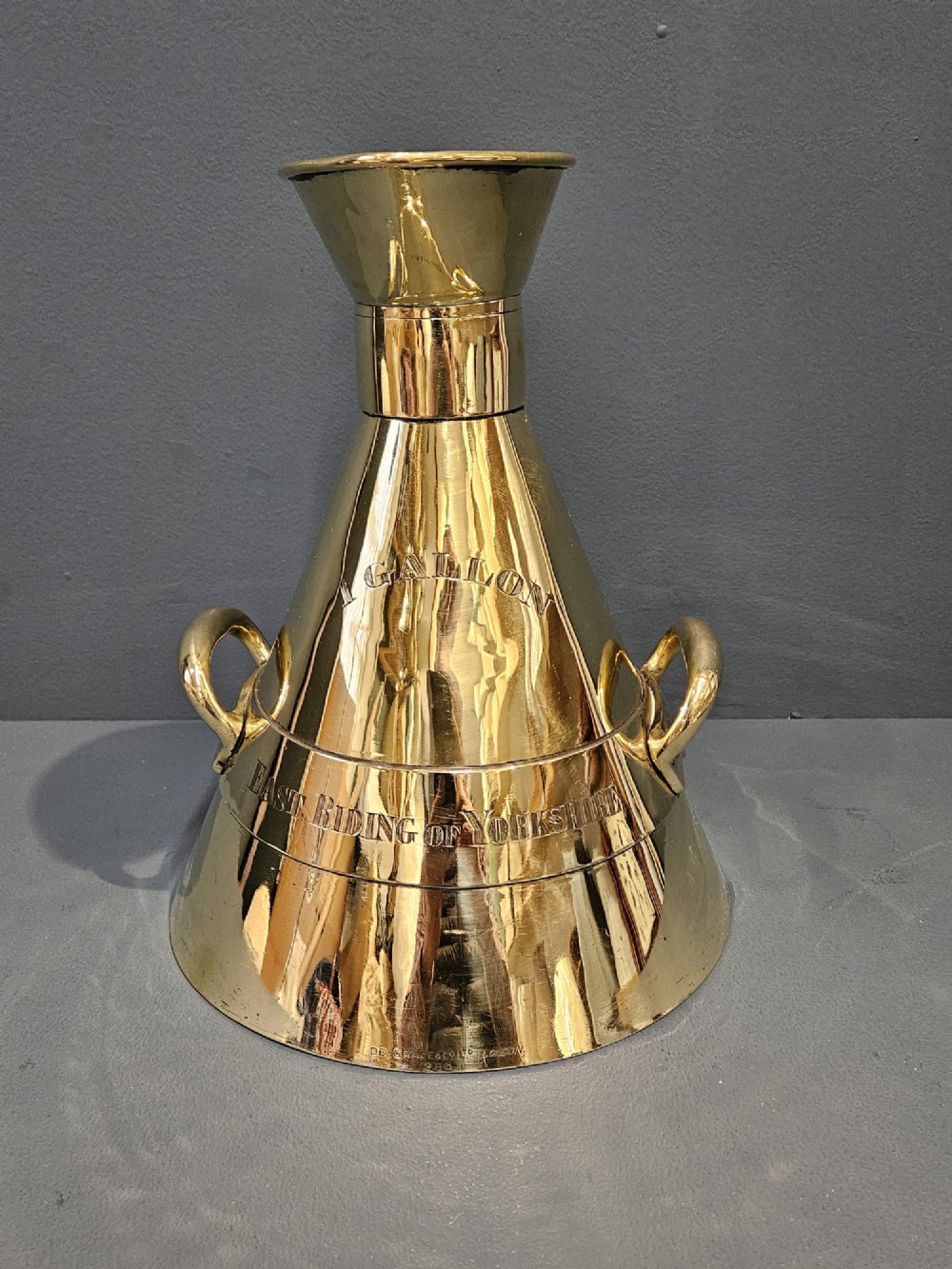 A polished Victorian brass one gallon capacity standard measure with a flared funnel top, conical body, twin loop handles, and official engravings. View III