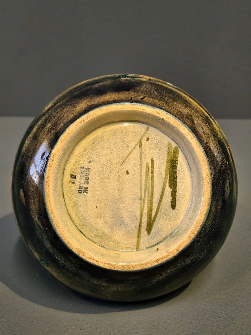 A small squat earthenware Moorcroft Eventide vase featuring tubelined trees against an orange and ochre twilight ground. View V