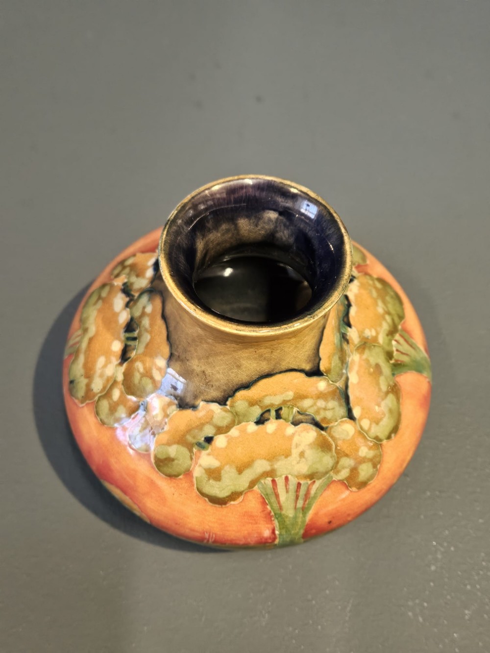 A small squat earthenware Moorcroft Eventide vase featuring tubelined trees against an orange and ochre twilight ground. View VIII