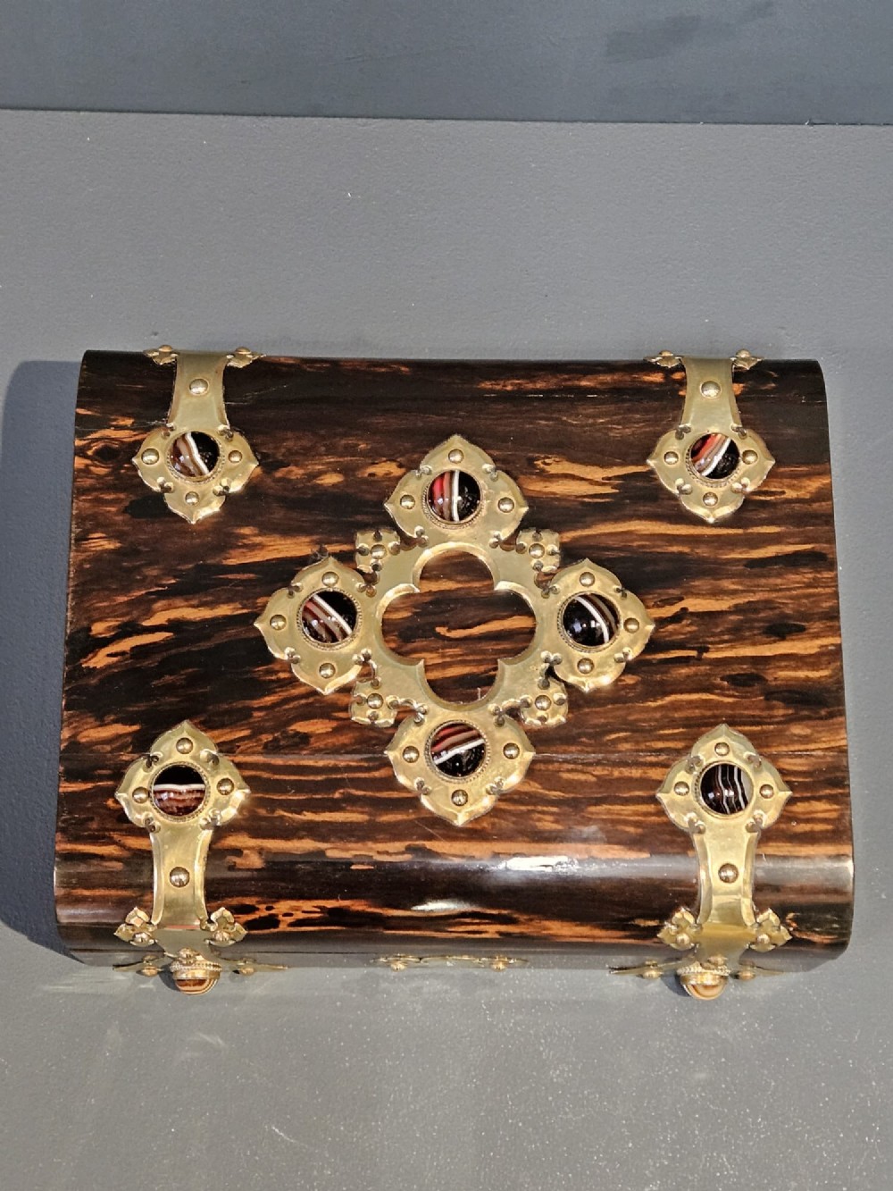 A dark coromandel wood box featuring decorative brass strapwork inset with rounded agate cabochons. View IX