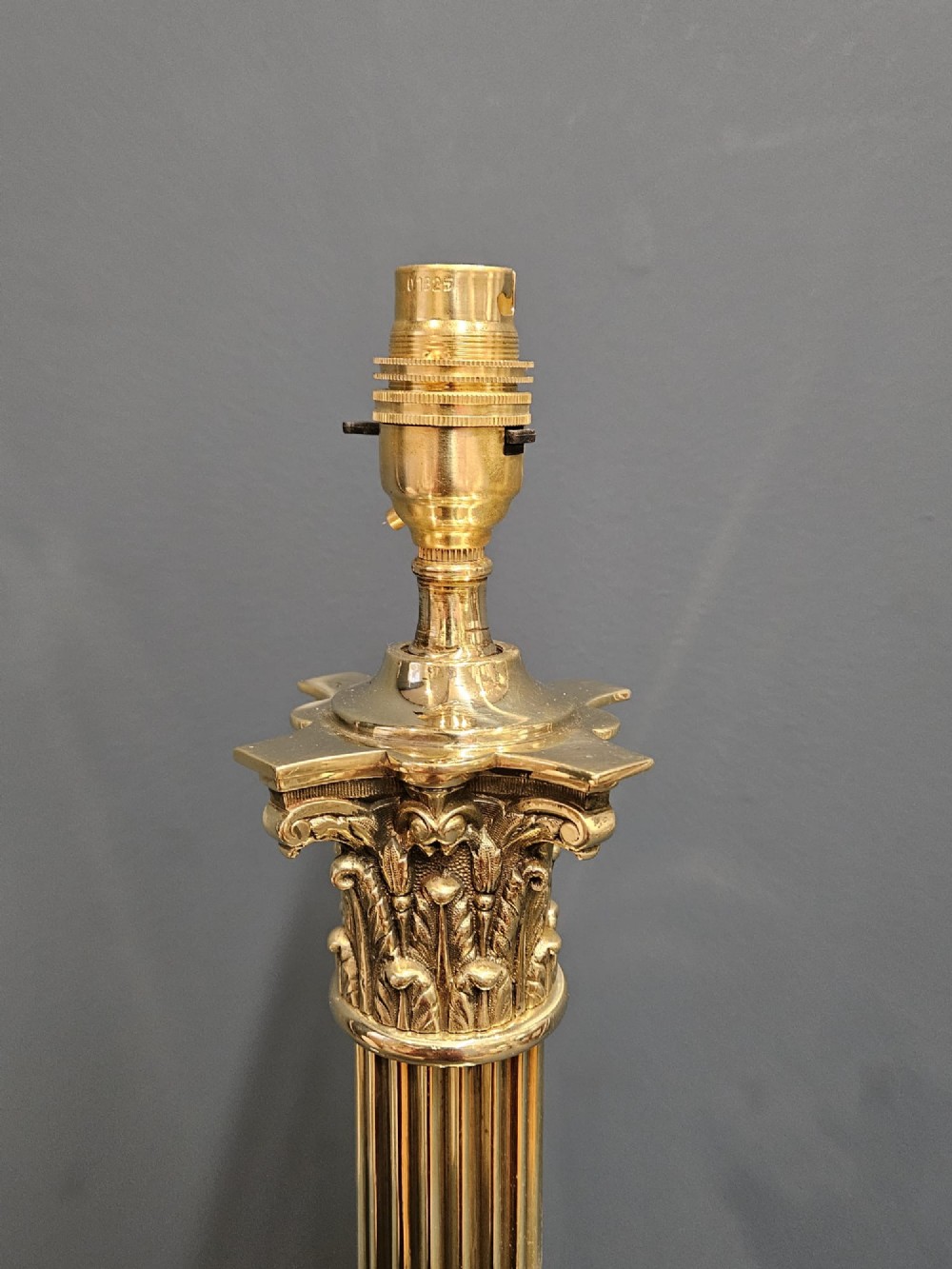 An Edwardian brass table lamp designed as a classical Corinthian column with a fluted shaft and stepped square base. View IV