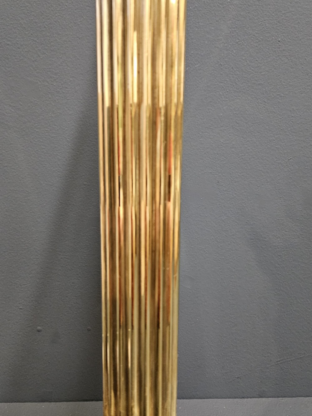 An Edwardian brass table lamp designed as a classical Corinthian column with a fluted shaft and stepped square base. View VII