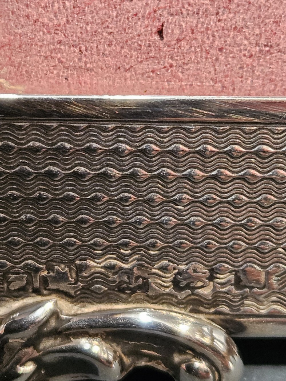 A rectangular George V sterling silver picture frame featuring engine-turned geometric engraving, ornate foliage corner mounts, and a circular top cartouche. View VI