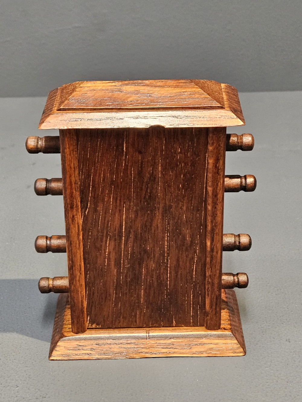 An Edwardian oak perpetual desk calendar featuring turned side knobs and central cutout apertures displaying the day, date, and month on printed fabric scrolls. View III