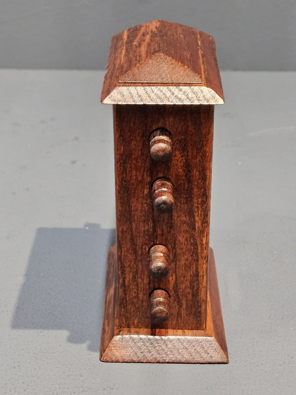 An Edwardian oak perpetual desk calendar featuring turned side knobs and central cutout apertures displaying the day, date, and month on printed fabric scrolls. View IV