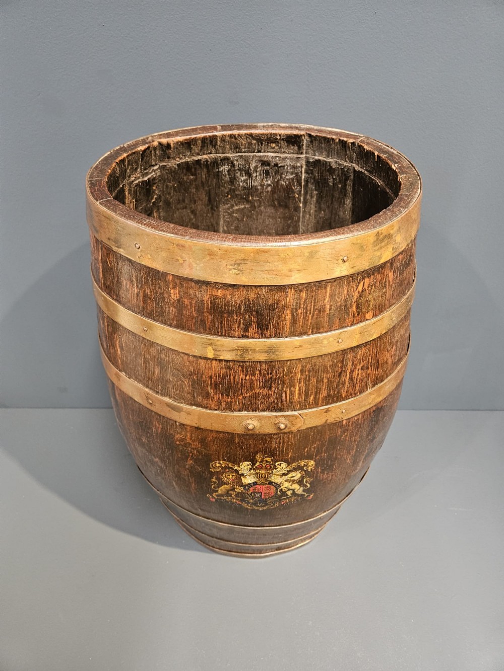 A Victorian dark oak coopered barrel stick stand fitted with brass hoops and displaying a royal coat of arms crest on the front. View II