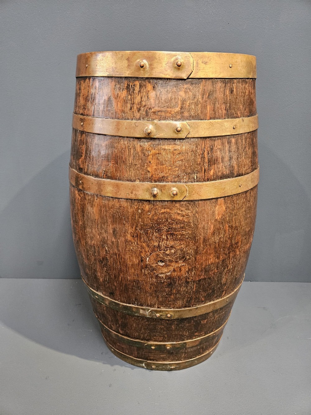 A Victorian dark oak coopered barrel stick stand fitted with brass hoops and displaying a royal coat of arms crest on the front. View V